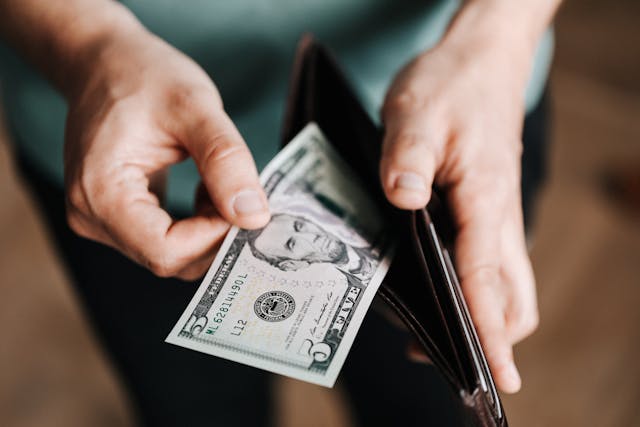 person holding a wallet with american cash inside